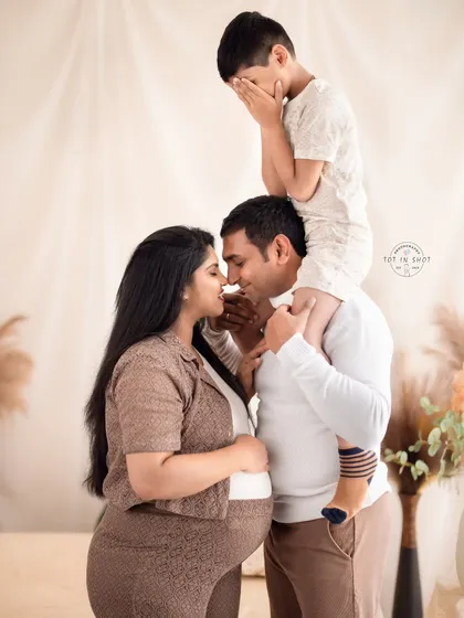 The whole family is part of the journey. This heartwarming family maternity photo captures a playful and intimate moment between the parents and the excited older sibling, celebrating the love that's about to grow.