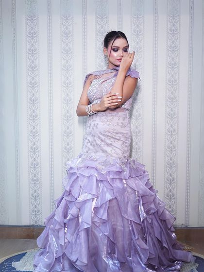 A full-length shot showing the dramatic ruffled trail of the lilac gown.
