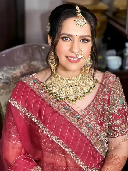 This front-facing portrait shows the complete bridal look. The makeup is balanced, with attention to both the eyes and lips, and the hair is elegantly swept up to showcase her jewelry.