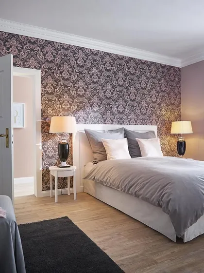 A deep purple and silver damask pattern creates a dramatic and romantic bedroom. This bold choice from the Trianon collection adds a sense of luxury and intimacy.