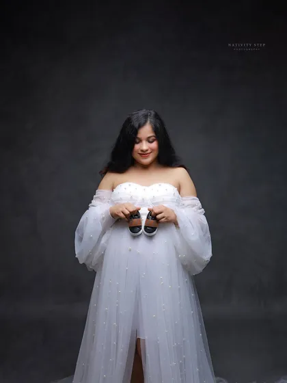 A sweet solo portrait holding a pair of tiny baby shoes. The mother-to-be's gentle expression is full of love and anticipation.