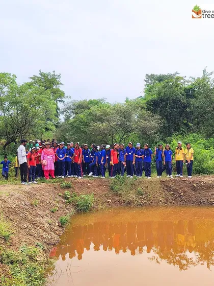 Students gather by a water body at the Honeywell Pune site. We teach them how forests and water sources are interconnected parts of a single ecosystem.
