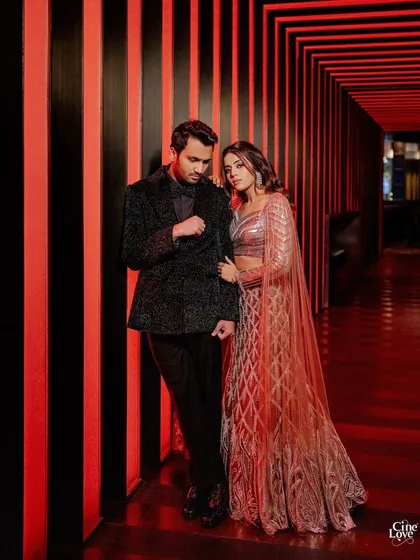 A moody, romantic portrait of the couple. His dark, textured suit and her embellished lehenga create a look of sophisticated glamour.