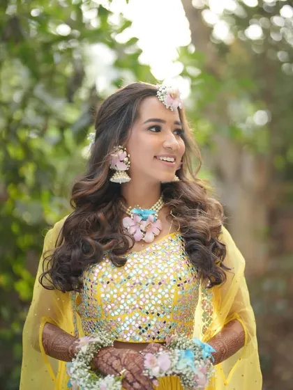 A beautiful, happy bride at her Haldi. Her pastel floral jewellery set was custom-made to complement the colours in her mirror-work lehenga.