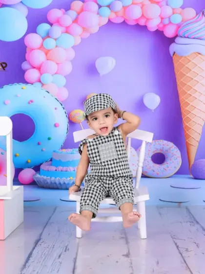 A full view of the vibrant and colorful sweet shop theme, perfect for a first birthday. The giant ice cream cone and donut props are a huge hit with the little ones.