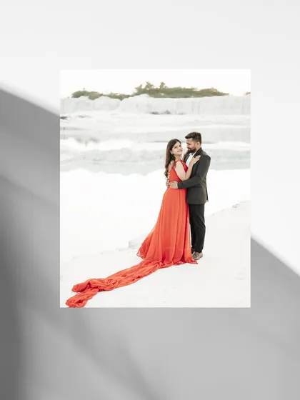 An elegant portrait of the couple at a white quarry, with the bride's long red train spread out beautifully behind her.