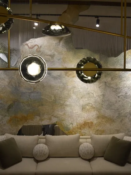 A detail of the Ceto chandelier at the India Art Fair. The fixture's organic, rippling glass forms provide a beautiful contrast to the raw, artistic texture of the wall behind it.
