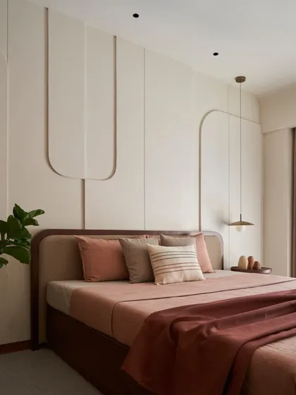 In this dusty rose bedroom, I used curved 3D cutouts on the wall to create subtle artwork. The 'less is more' philosophy is evident here, focusing on texture, soft colors, and a feeling of deep calm.