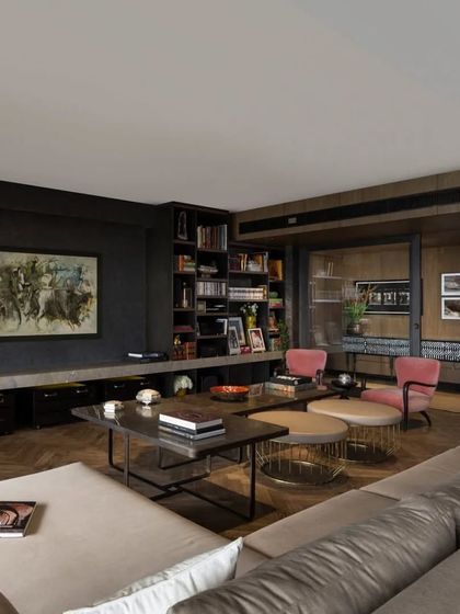 This angle shows the flow from the living room towards the entrance corridor in the Caitriona apartment. The herringbone wood floor defines the seating area, while the mix of contemporary furniture and a curated bookshelf wall creates a space that is both stylish and lived-in.