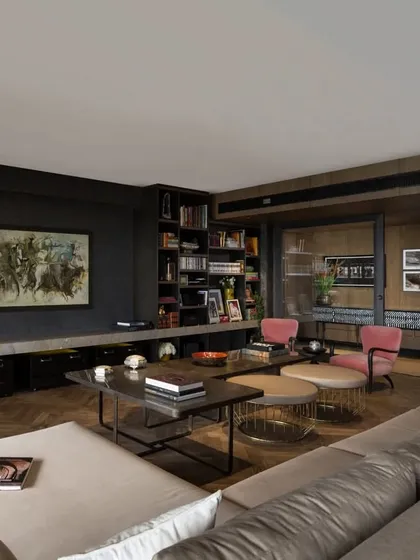 The living room of the Caitriona apartment, featuring a custom TV wall with a stone slab and moveable leather drawers. The space is furnished with an eclectic mix of custom tables, ottomans, and a vintage Louis XV Love seat.