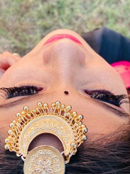 A similar artistic shot from a different angle, emphasizing the intricate details of the eye makeup and the traditional 'chandbali' style maang tikka.