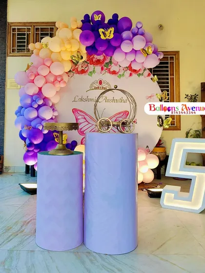 A butterfly-themed party for a fifth birthday, using a rich color palette of purple, pink, and yellow. The setup includes a custom backdrop and a large light-up number '5'.
