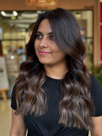A three-quarter view of a soft balayage on dark hair. The lighter pieces are concentrated on the ends and around the face for a modern, flattering style.