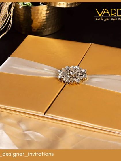 A truly glamorous invitation featuring a golden folio case adorned with a sparkling crystal brooch. This design exudes luxury and is perfect for a high-end wedding or a grand 50th-anniversary celebration.
