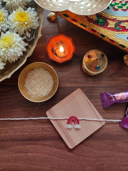A cute and simple handmade rakhi featuring a small embroidered rainbow. This is a unique design perfect for celebrating the bond of siblings.