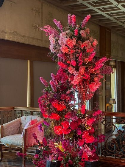 A towering, spiral-like floral installation creates a dramatic statement piece. The arrangement uses a gradient of pinks, drawing the eye upward and adding a sense of dynamic movement to the decor.