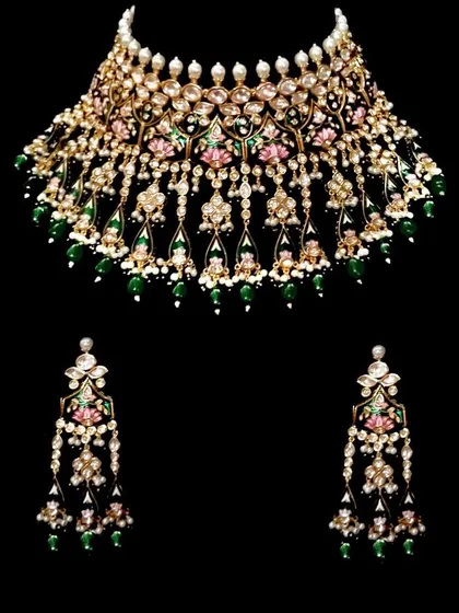 A beautiful Meenakari choker with pink lotus motifs and green bead drops. This is an artistic and elegant rental piece.