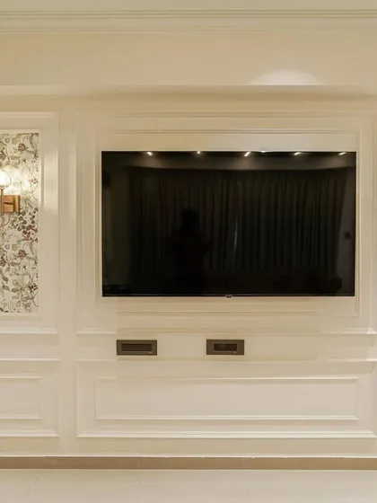 A detailed shot of the elegant TV wall unit from image 61, featuring classic moulding and floral wallpaper panels.