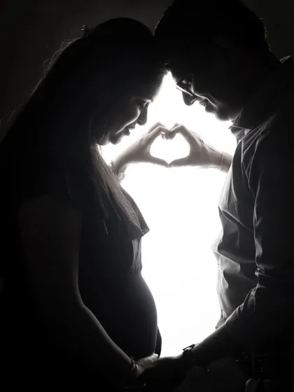 A tender silhouette of an expecting couple. The backlighting creates a beautiful halo effect, emphasizing their connection and the shape of the baby bump.