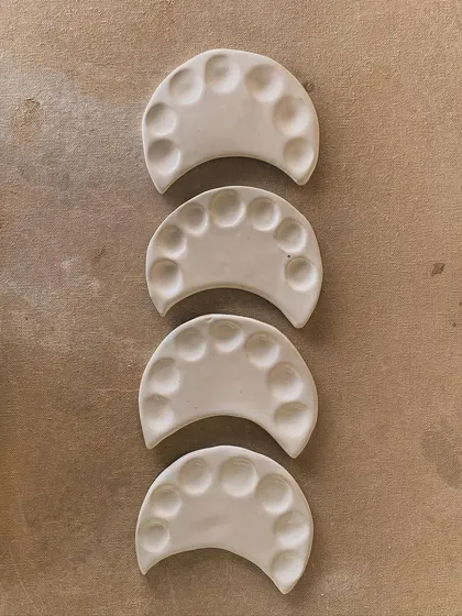 A set of four moon-shaped paint palettes, ready for glazing. Simple, elegant, and functional.