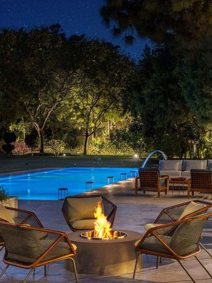 The poolside seating area by night, featuring a comfortable fire pit lounge. The entire outdoor space is designed for entertaining and relaxation, extending the home's living area into the landscape.