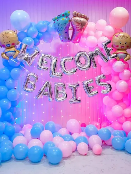 A fun "Welcome Babies" decoration for twins. The backdrop is made of blue and pink balloons with a curtain of fairy lights, perfect for celebrating the arrival of two little ones.