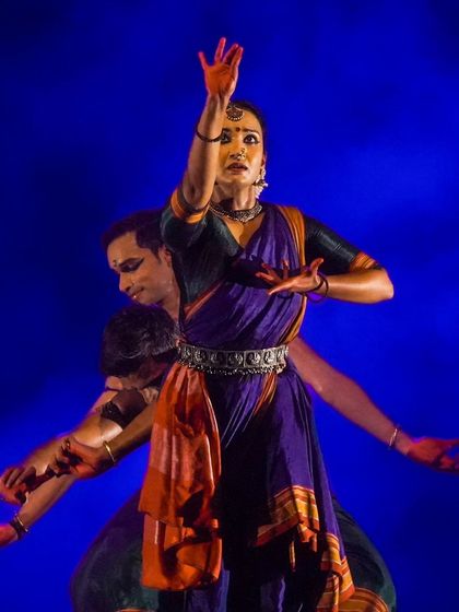 A dynamic group pose from 'Nagamandala' against a vibrant blue background. The choice of costume and lighting colors is deliberate to enhance the mood of each scene.