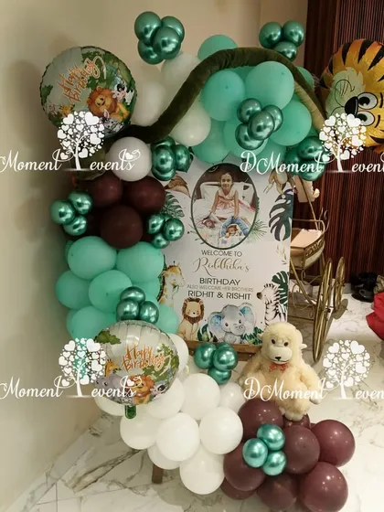 A welcome sign for the jungle-themed party, framed by a creative balloon arrangement that includes tiger and monkey foil balloons.