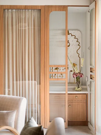 For the mandir in the Kābu home, we created a space that is minimal yet warm and elegant. We designed a marble back panel with brass inlaid lotuses and religious motifs, enclosed by a fluted glass door to add to the pious charm.