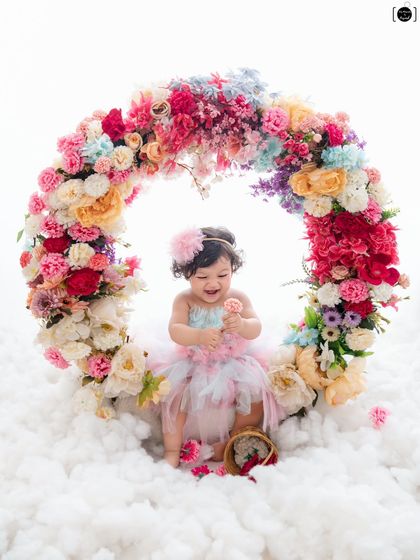 This little one is a picture of pure delight, laughing as she plays with a flower in our magical floral ring setup.
