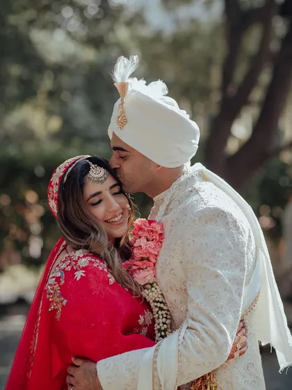 A moment of pure, unscripted love. The groom's gentle kiss on the bride's forehead is a testament to their beautiful connection.