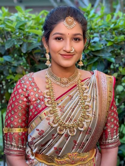A soft and glowing look for the sister of the bride, featuring a beautiful silver and red saree with traditional gold jewellery.