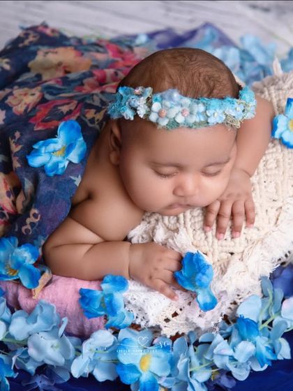 A beautiful portrait using deep blues and floral patterns. The combination of the floral wrap and the scattered blue petals creates a rich and unique look.