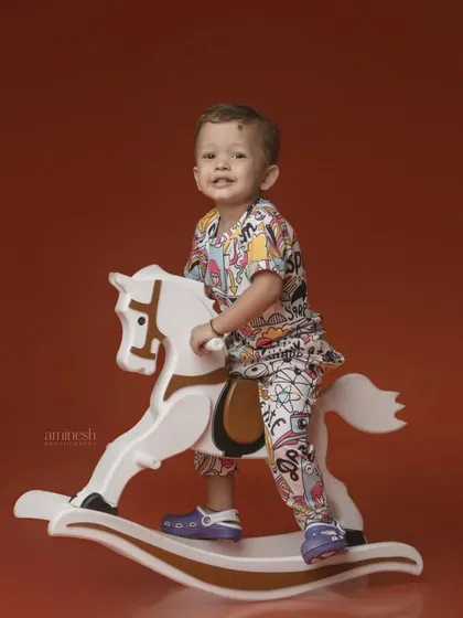 Giddy up! A fun shot of a little boy in a colorful outfit riding a classic white rocking horse. This timeless toy always brings out the smiles.