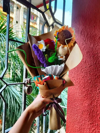 A shot of my mixed crochet bouquet held against a window, with the natural light highlighting the vibrant colors of the yarn.