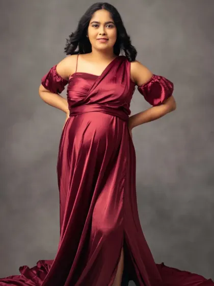 A full-length view of our beautiful burgundy satin gown, showcasing its flowing train and elegant off-the-shoulder design.