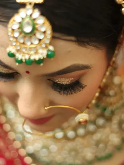 A detailed close-up of the bride's maang tikka and shimmering eyeshadow. We pay close attention to the artistry of bridal makeup and jewelry in our portrait photography.