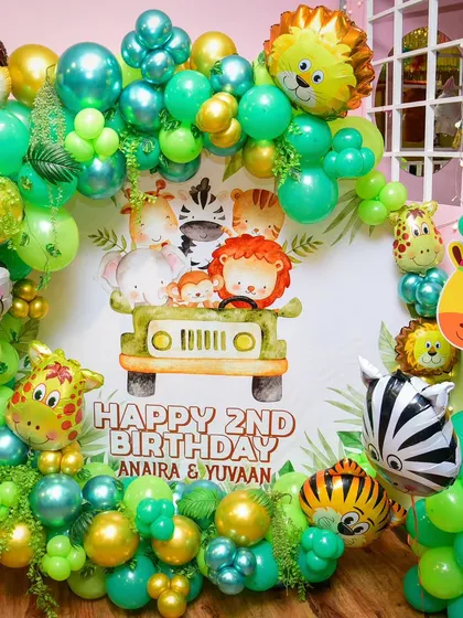 Welcome to the jungle! This vibrant setup for a second birthday includes a custom backdrop with safari animals, animal-print balloons, and lots of leafy green details.