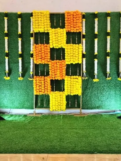 A traditional backdrop setup with a marigold checkerboard pattern on a grass wall, ready for seating to be added.