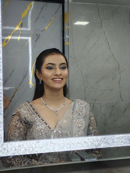 A mirror selfie of a model in a grey lehenga, showing a happy and candid moment.
