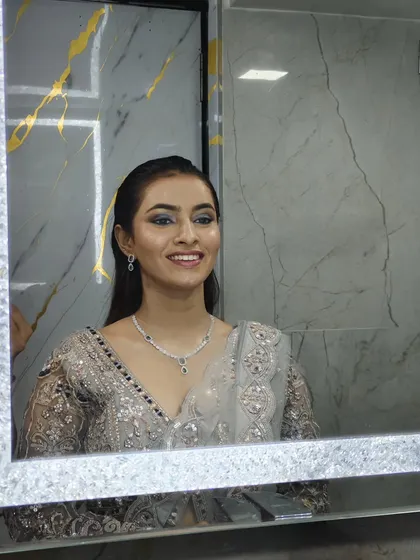 A client's reflection in the mirror, smiling while wearing our silver and blue lehenga.