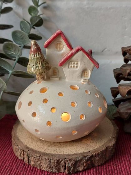 This glowing tealight holder features a tiny village scene on a snowy hill. When you place a candle inside, the light shines through the holes, creating a magical winter wonderland.