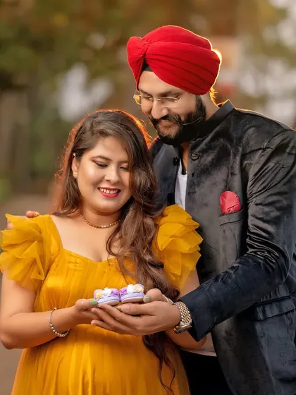 An outdoor couple's portrait with a sweet, interactive element. Sharing these little cupcakes adds a playful and personal touch to their maternity session in the park.