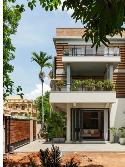 The renovated and extended Ananda residence in Hyderabad, showcasing a facade of striated compressed earth blocks. This design choice was not just for aesthetics but also for thermal comfort, creating a self-shading pattern that reduces heat gain.
