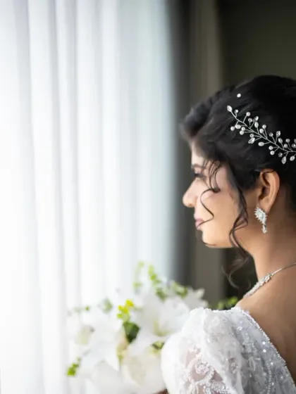 A beautiful profile shot of the bride. This portrait highlights her elegant hairstyle and the delicate details of her veil and dress.