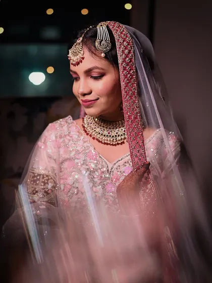 A beautiful bridal portrait with a slow shutter effect, creating a sense of movement and magic around her. The soft pinks of her outfit and makeup add to the romantic feel.