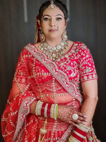 A gorgeous bride ready for her big day. This image captures the complete look, from the intricate hairstyle to the stunning red lehenga and heavy jewelry.