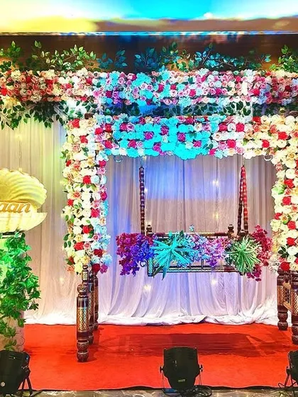 A complete stage for a Namkaran Sohala. The setup includes a decorated cradle, cute baby cutouts, and the special seashell prop on a pedestal, ready for the big name reveal moment.