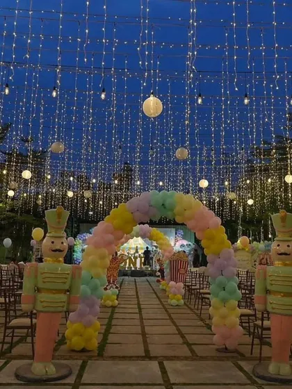 I love how lighting can completely change a space. For this pastel carnival party, a canopy of fairy lights and a colorful balloon arch with giant toy soldiers created a magical entryway, setting a spectacular tone for the evening celebration.