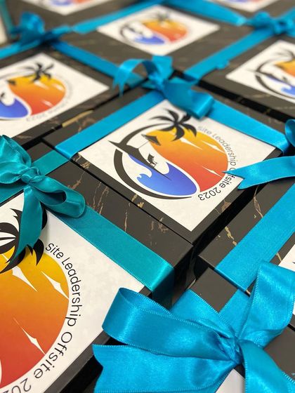A close-up of the branded boxes for the leadership offsite, tied with a bright blue ribbon for a polished finish.